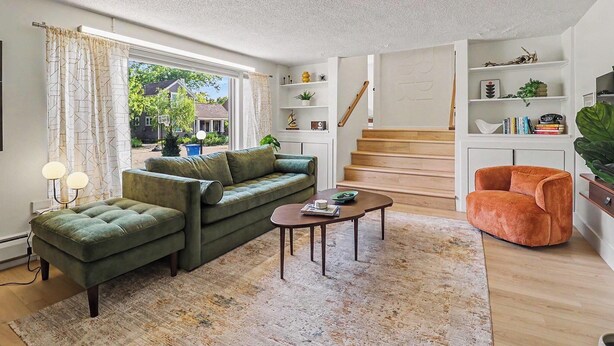 Un salon comprenant un canapé, un fauteuil, une table basse et un escalier menant à un autre niveau.