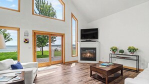 A spacious living room with a fireplace, a television, and a view of the outdoors. - Portage Lake Beachfront with Dock at North Point (Onekama)