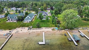 A residential area with houses, a dock, and a grassy field. - Portage Lake Beachfront with Dock at North Point (Onekama)