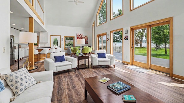 A spacious living area with a high ceiling, large windows, and a view of the outdoors. - Portage Lake Beachfront with Dock at North Point (Onekama)