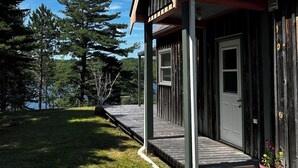Eine Holzhütte mit Veranda, Tür und einem kleinen Garten.