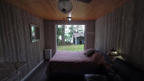Une chambre à coucher avec un lit, un ventilateur de plafond, une fenêtre et une vue sur l’extérieur.