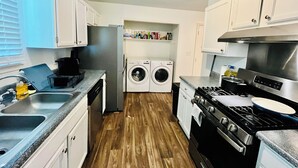 Een kleine keuken met een wasmachine, een koelkast, een fornuis en een gootsteen.