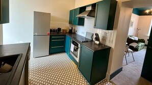 Eine kleine Küche mit Kühlschrank, Herd und ätzend-blauen Schränken.