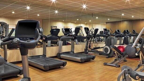 Una palestra con tapis roulant, macchinari per pesi e uno specchio a parete.