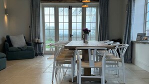 A dining area with a table, chairs, and a vase of flowers. - Stunning Countryside House with Pool and Hot Tub (Wiltshire)
