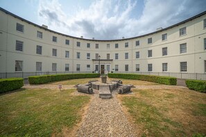 Ein großes, geschwungenes Gebäude mit Innenhof, zahlreichen Fenstern und einem symmetrischen Design.