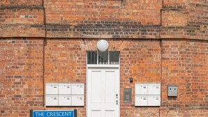 Un edificio de ladrillo con una puerta blanca, buzones y un letrero que dice 'The Crescent'.