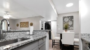 A modern kitchen with granite countertops, a built-in sink, and a ceiling fan. - Lake Front - Corner Unit - 2 Bedroom 2 Bath (Brandon)