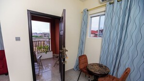 Una stanza con un balcone, un tavolo rotondo con sedie e una finestra con tende.