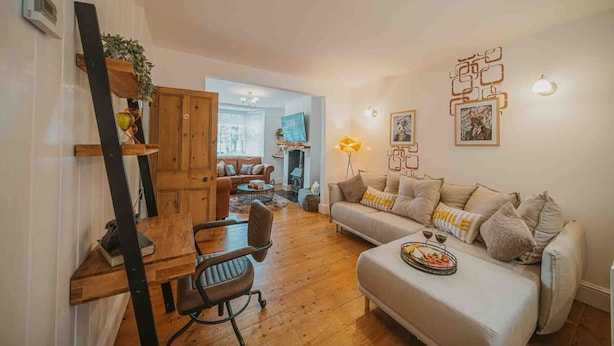 A cozy living room with a sofa, coffee table, and a dining area with a wooden table and chairs. - Cotswolds   2BD   1 Bath   Garden   City Centre (Gloucestershire)