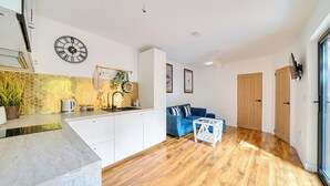 A modern kitchen with white cabinets, a clock, and a honeycomb backsplash. - Nottingham Cabin Sleeps 4 - Parking & Patio (Nottingham)