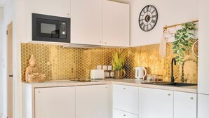 A kitchen with white cabinets, a microwave, a clock, and a plant. - Nottingham Cabin Sleeps 4 - Parking & Patio (Nottingham)
