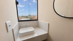 Un baño con ventana, lavabo y espejo.