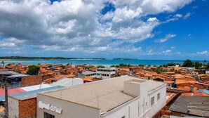 Un pueblo costero con edificios de techo rojo, un cielo azul despejado y vista al mar.