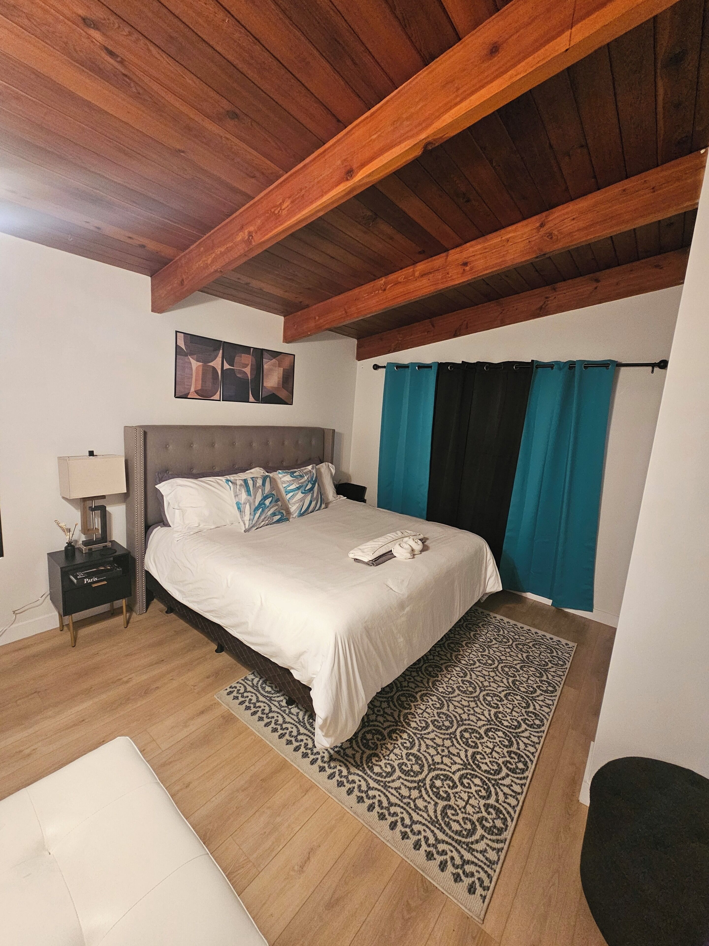 A bedroom with a bed, nightstand, lamp, and a patterned rug.