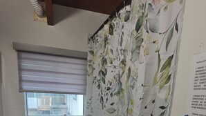Een badkamer met douchegordijn, toilet, wastafel en raam.