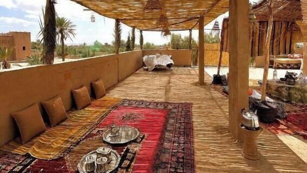 An outdoor seating area with a thatched roof, cushions, and a view of the surrounding landscape.
