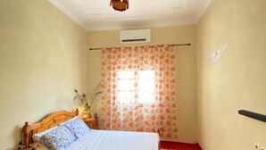 A bedroom with a bed, nightstand, and a window with curtains.