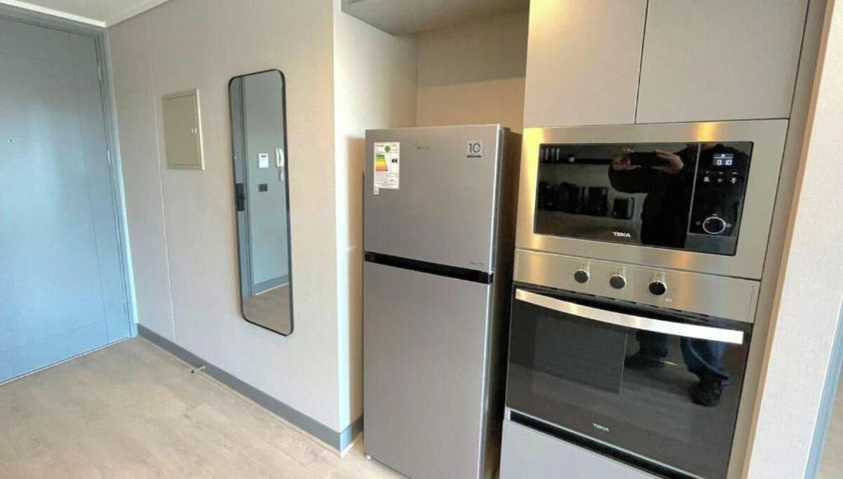 Eine Küche mit Kühlschrank, Backofen und Mikrowelle.