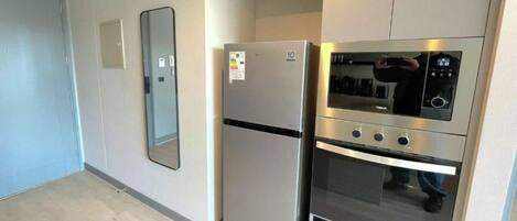 Eine Küche mit Kühlschrank, Backofen und Mikrowelle.
