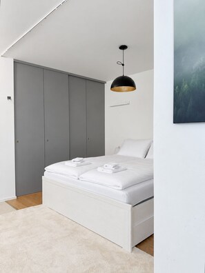 A modern bedroom with a bed, grey wardrobe, and a pendant light. - Luxury Two-Story Apartment in the Heart of Stockholm (Stockholm)