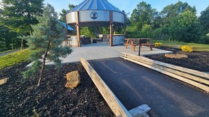 A gazebo with a circular roof and a central emblem, surrounded by a landscaped garden with a paved area and wooden benches. - Southern Charm (Sevierville)