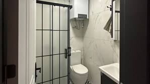 Un baño con inodoro, cabina de ducha y lavamanos.