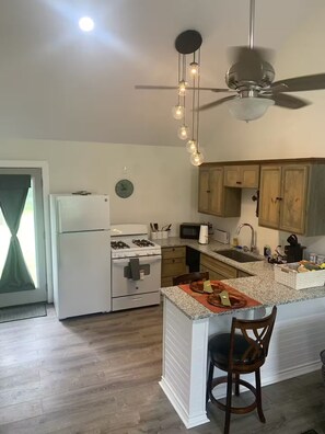 A kitchen with a central island, a refrigerator, stove, microwave, and wooden cabinets. - Welcome to Lilly's Pad (Aquilla)