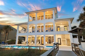 Ein mehrgeschossiges Haus mit Pool, Balkonen und einer überdachten Terrassenfläche.