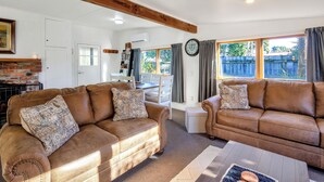 A living room with two brown leather sofas, a fireplace, a dining area, and large windows with curtains.