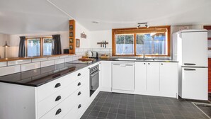 A modern kitchen with white cabinets, a black countertop, a built-in oven, and a dishwasher.