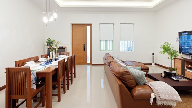Uma sala de estar moderna com área de jantar, sofá e televisão.