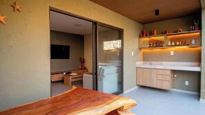 A modern kitchen with a wooden countertop, a glass door leading to a dining area, and a shelf with decorative items. - Azuk Milagres 6 p Close to Patacho Beach by MME (Porto de Pedras)