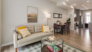 Een woonkamer met een bank, salontafel en een eethoek met stoelen en een tafel.