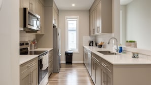 Een moderne keuken met roestvrijstalen apparatuur, een centraal eiland met een spoelbak en lichte kasten.