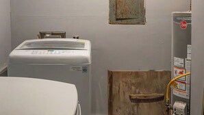 A laundry room with two washing machines, a water heater, and a wooden door. - Spacious Southern Charm with Pool Table! (Jonesboro)