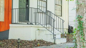 A house with a front porch, a green door, and a small staircase leading to the entrance. - Spacious Southern Charm with Pool Table! (Jonesboro)