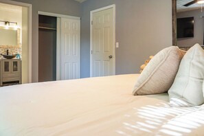 A bedroom with a bed, a wardrobe, a mirror, and a door. - Spacious Southern Charm with Pool Table! (Jonesboro)