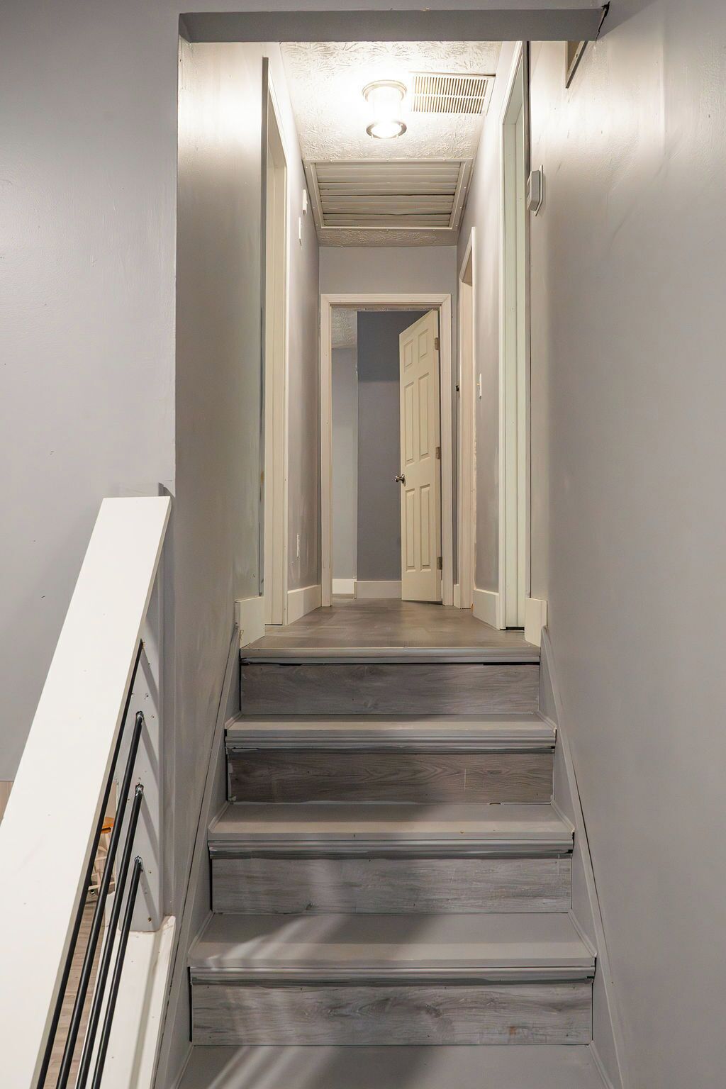A staircase with a handrail, leading to a door at the top.