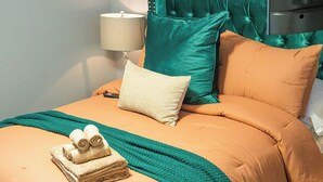 A bed with a teal throw blanket, a beige pillow, and two rolled towels. - Spacious Southern Charm with Pool Table! (Jonesboro)