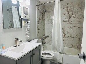A bathroom with a shower, toilet, sink, and a mirror. - Alamo Inn & Suites (Gillette)