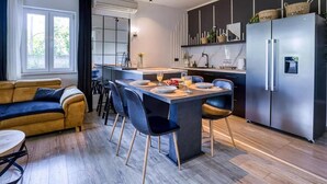 Eine moderne Küche mit Kochinsel, dunklen Schränken und einem Edelstahl-Kühlschrank.