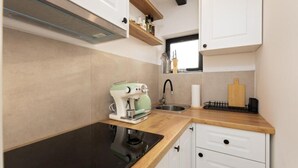Een kleine keuken met een ingebouwde kookplaat, een spoelbak en witte keukenkastjes.