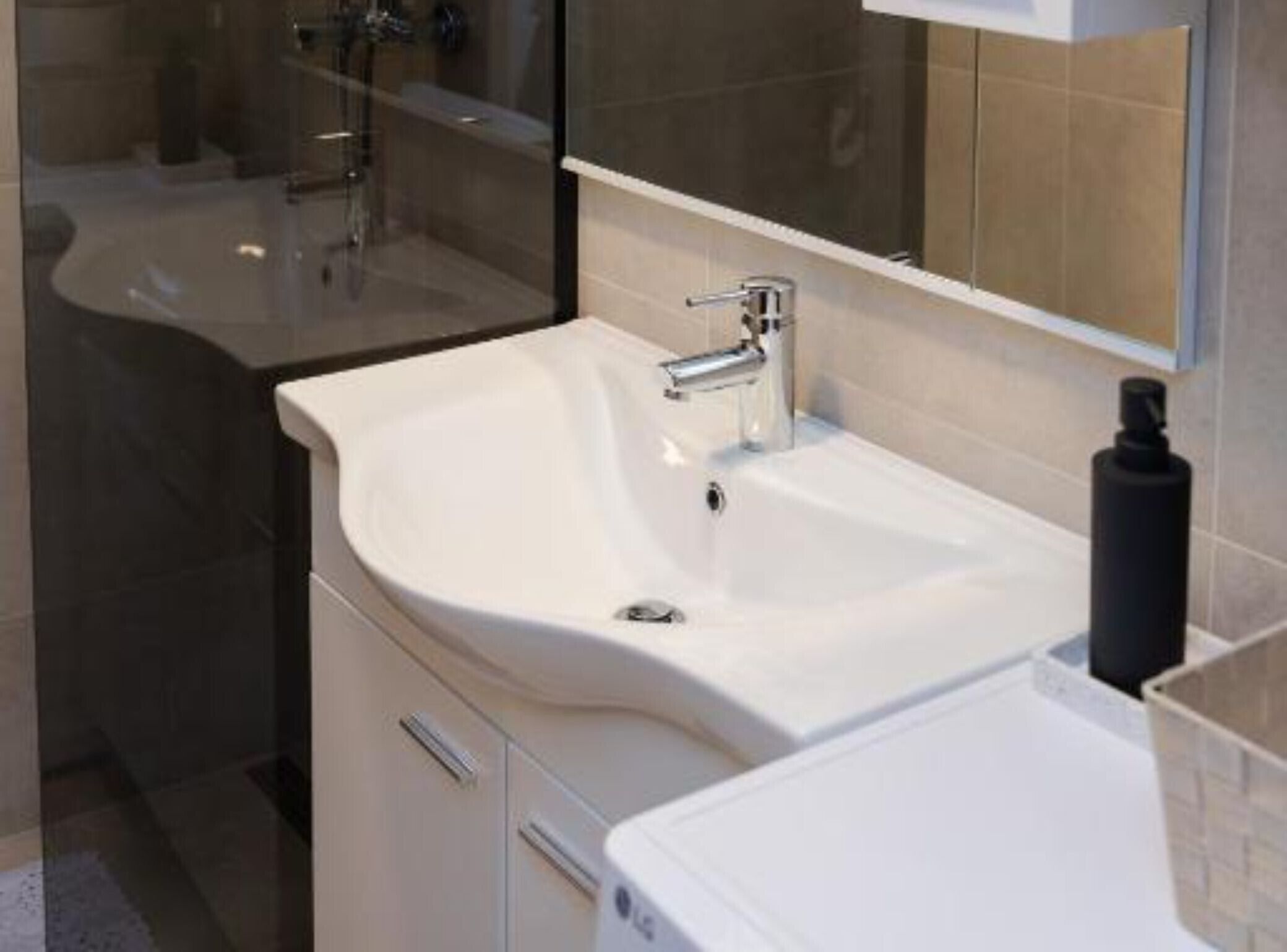 Un bagno moderno con un lavandino bianco, uno specchio e uno spazio doccia.