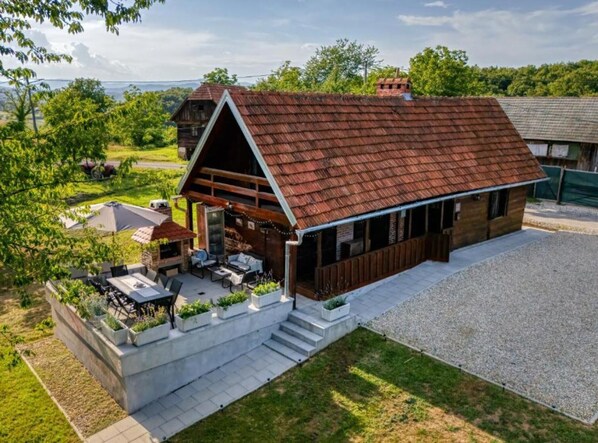 Ein rustikales Scheunenhaus mit geneigtem Dach, Sitzbereich im Freien und einer Schotterauffahrt.