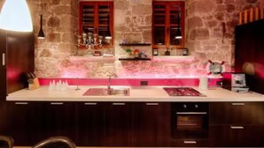 A kitchen with stone walls, wooden cabinets, a central island, and pendant lighting. - Four Bedroom House with Terrace (Komiza)
