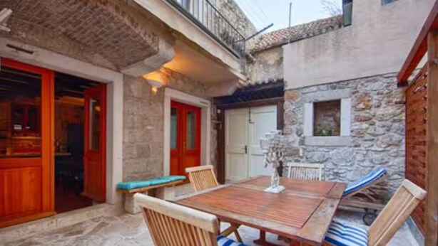 A stone building with a wooden table and chairs, a bench, and a small window. - Four Bedroom House with Terrace (Komiza)
