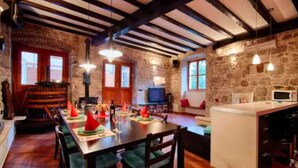 A dining area with a wooden table, chairs, and a stone wall. - Four Bedroom House with Terrace (Komiza)
