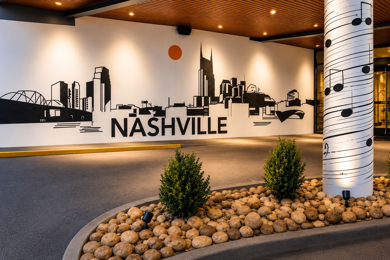 A wall mural of Nashville's skyline with a large 'NASHVILLE' text, a decorative pillar with musical notes, and a landscaped area with rocks and shrubs.